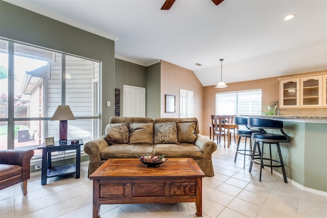 living room featuring ceiling fan, light tile patterned flooring, vaulted ceiling, ornamental molding, and baseboards