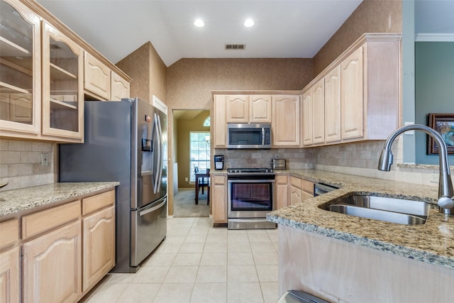 kitchen featuring appliances with stainless steel finishes, light brown cabinets, a sink, light stone countertops, and recessed lighting