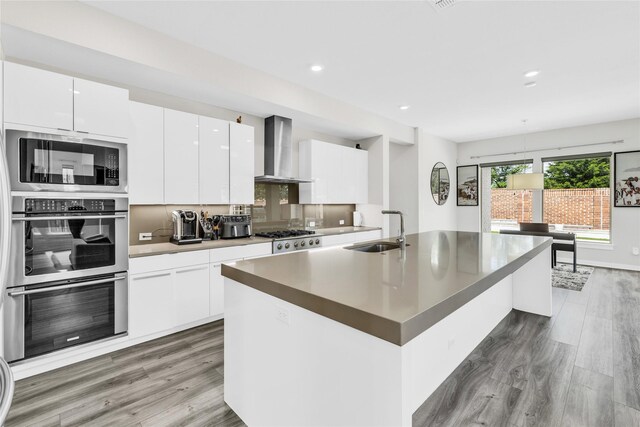 5160 Statesman Ln, Frisco, TX 75036 - kitchen featuring wall chimney exhaust hood, a sink, appliances with stainless steel finishes, modern cabinets, and light wood finished floors