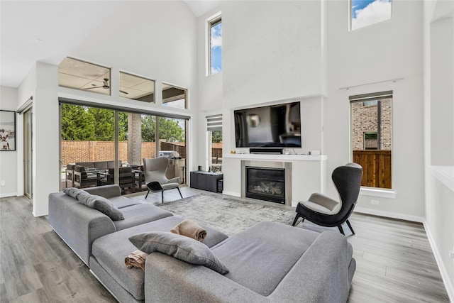 5160 Statesman Ln, Frisco, TX 75036 - living room featuring a high ceiling, a glass covered fireplace, wood finished floors, and baseboards