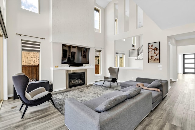 5160 Statesman Ln, Frisco, TX 75036 - living room with a towering ceiling, wood finished floors, a glass covered fireplace, and baseboards