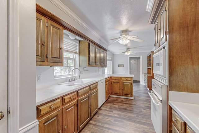 kitchen with white appliances, a sink, a peninsula, a ceiling fan, and dark wood finished floors
