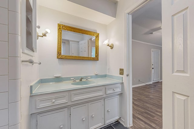 bathroom with crown molding, vanity, wood finished floors, and baseboards