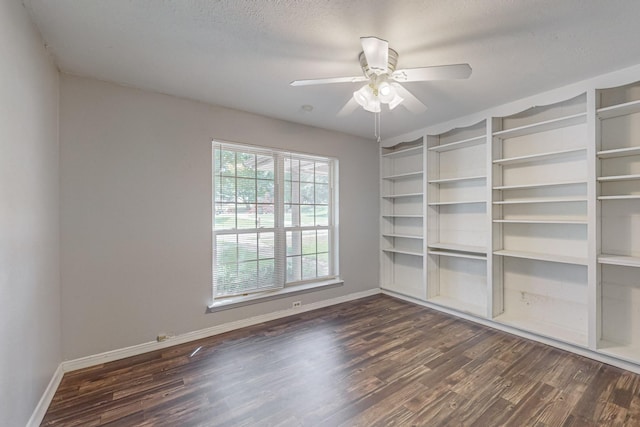 unfurnished room with dark wood-style flooring, baseboards, ceiling fan, and a textured ceiling