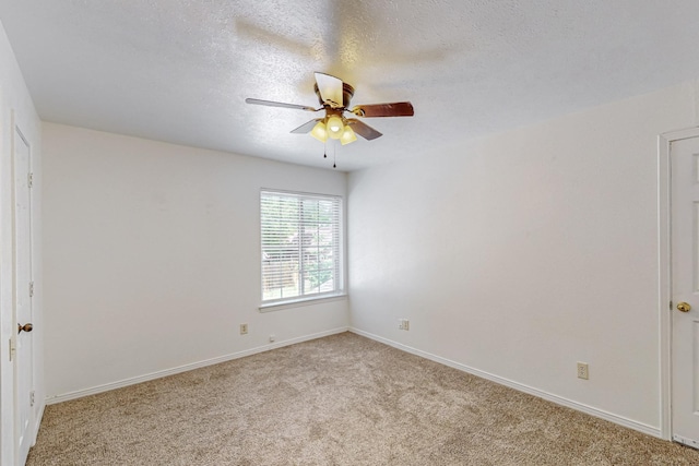 empty room featuring a ceiling fan, light colored carpet, baseboards, and a textured ceiling