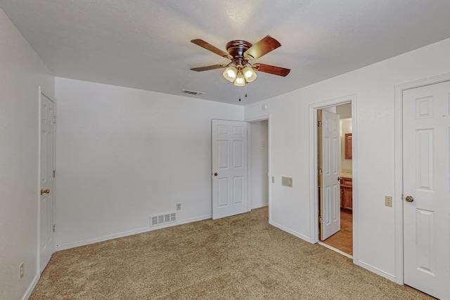 unfurnished bedroom featuring light carpet, baseboards, ensuite bathroom, and ceiling fan