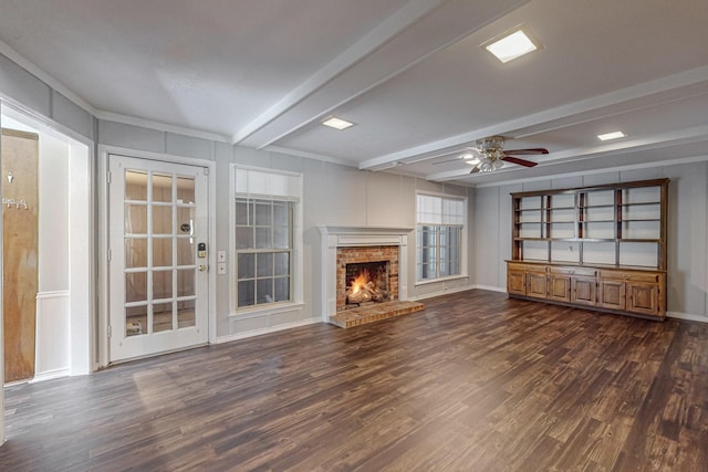 unfurnished living room featuring dark wood finished floors, beam ceiling, a ceiling fan, a brick fireplace, and baseboards