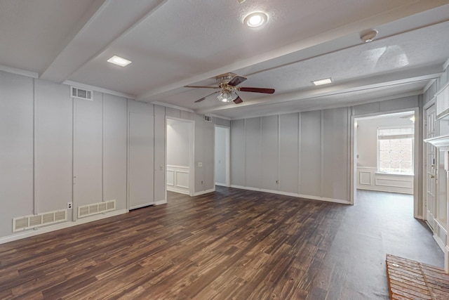 unfurnished living room featuring a decorative wall, beamed ceiling, a ceiling fan, and dark wood finished floors