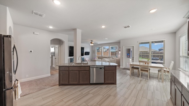 kitchen featuring appliances with stainless steel finishes, open floor plan, arched walkways, a sink, and recessed lighting