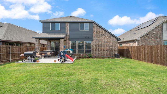 rear view of property featuring a patio, brick siding, a shingled roof, and a hot tub