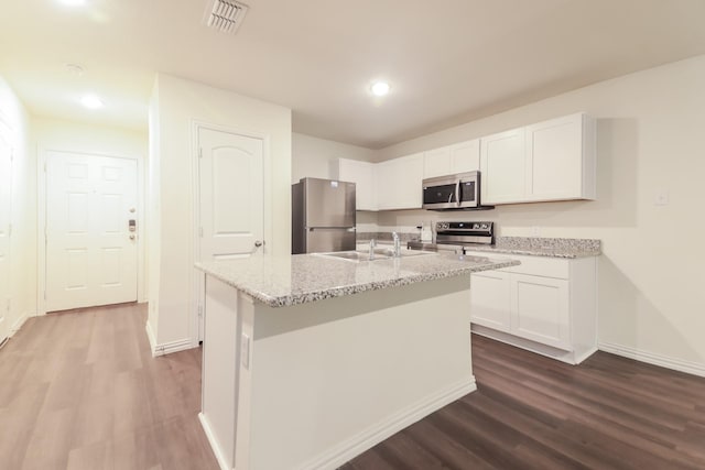 510 E Shepherd St, Denison, TX 75021 - kitchen featuring appliances with stainless steel finishes, dark wood-type flooring, white cabinetry, light stone countertops, and a sink