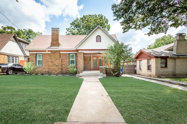 view of front of property with french doors, brick siding, a front lawn, and a chimney