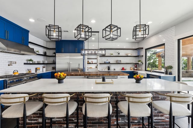 1210 Emerald Sound Blvd, Oak Point, TX 75068 - kitchen featuring open shelves, blue cabinetry, under cabinet range hood, decorative backsplash, and recessed lighting