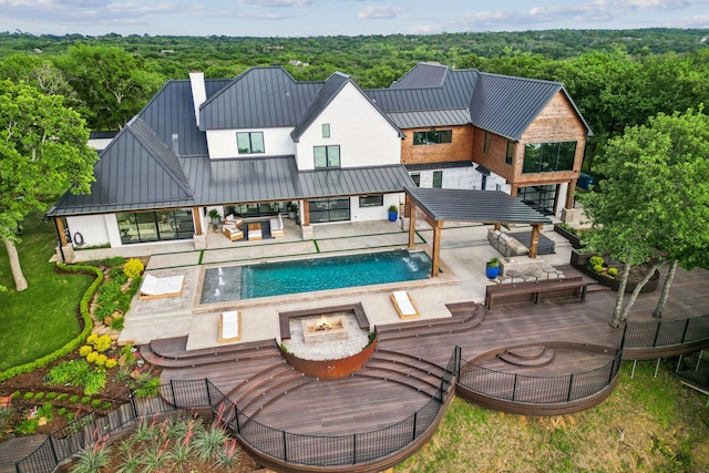 1210 Emerald Sound Blvd, Oak Point, TX 75068 - rear view of house featuring a standing seam roof, an outdoor living space with a fire pit, a fenced backyard, a view of trees, and an outdoor pool
