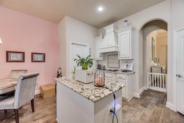 1537 Firenza Ct, Mclendon Chisholm, TX 75032 - kitchen featuring light wood-style floors, white cabinetry, light stone countertops, backsplash, and premium range hood