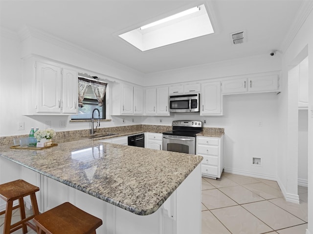 3804 Chestnut St, Fort Worth, TX 76137 - kitchen featuring appliances with stainless steel finishes, a peninsula, a sink, light stone countertops, and a skylight