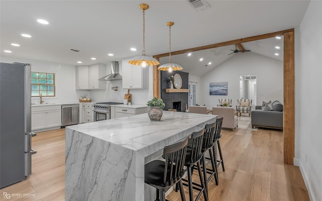 4131 Waller Dr, Shreveport, LA 71119 - kitchen with stainless steel appliances, wall chimney range hood, light wood-style floors, white cabinetry, and recessed lighting