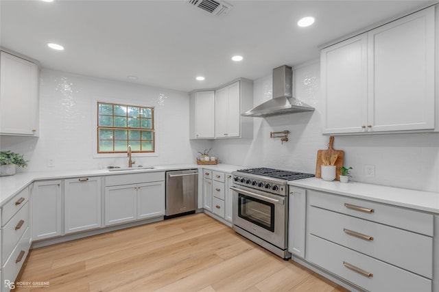 4131 Waller Dr, Shreveport, LA 71119 - kitchen featuring appliances with stainless steel finishes, a sink, wall chimney range hood, backsplash, and light wood-style flooring