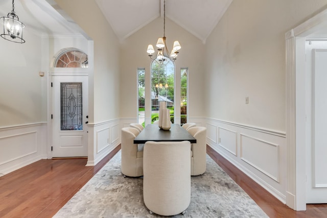 907 Sunpoint Cir, Rockwall, TX 75087 - dining room featuring a chandelier, wood finished floors, a decorative wall, wainscoting, and vaulted ceiling