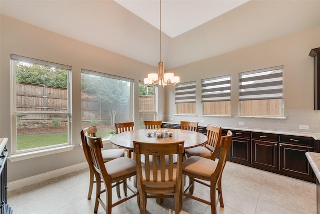 dining area with a chandelier, plenty of natural light, light tile patterned floors, baseboards, and vaulted ceiling