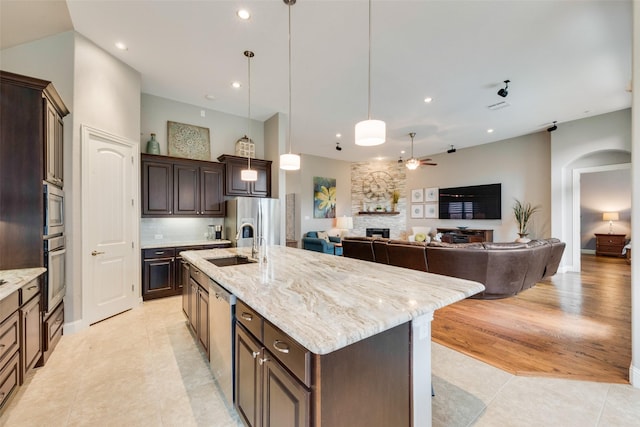 kitchen featuring stainless steel appliances, a kitchen island with sink, a fireplace, light tile patterned floors, and recessed lighting