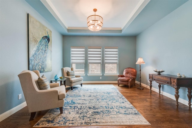 sitting room featuring a chandelier, a tray ceiling, baseboards, and wood finished floors