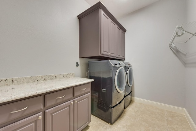 laundry room with washing machine and clothes dryer, cabinet space, and baseboards