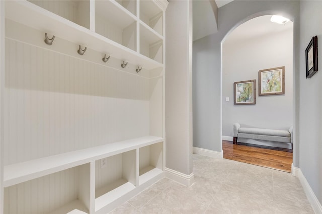 mudroom featuring arched walkways, tile patterned floors, and baseboards