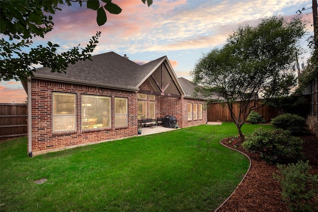 back of property with brick siding, a shingled roof, and a patio area