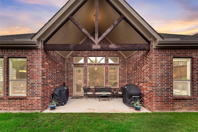 patio terrace at dusk with grilling area, outdoor lounge area, and a lawn