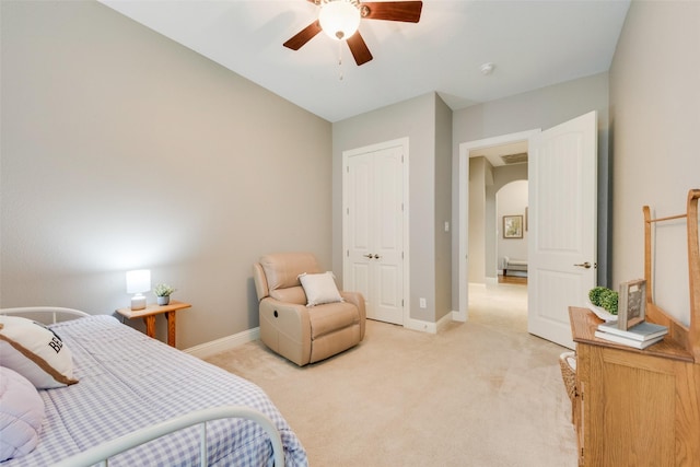 bedroom with light colored carpet, baseboards, arched walkways, a ceiling fan, and a closet