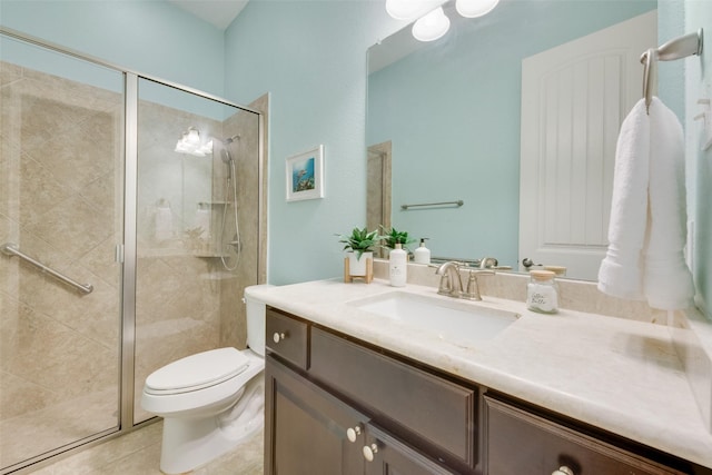 bathroom featuring toilet, vanity, a stall shower, and tile patterned floors