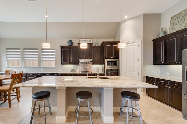 kitchen featuring appliances with stainless steel finishes, under cabinet range hood, a kitchen bar, a sink, and lofted ceiling