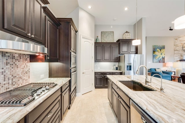 106 Magnolia Ln, Hickory Creek, TX 75065 - kitchen with appliances with stainless steel finishes, a sink, under cabinet range hood, light stone counters, and decorative backsplash