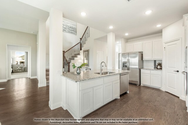 kitchen with a sink, stainless steel appliances, dark wood-style flooring, light stone countertops, and recessed lighting