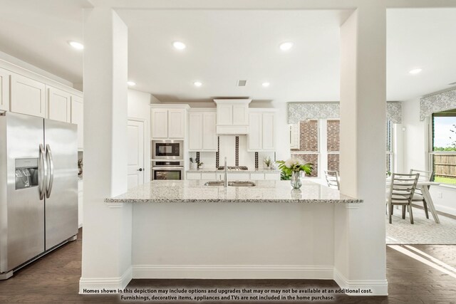 kitchen with appliances with stainless steel finishes, a sink, dark wood-style flooring, baseboards, and recessed lighting