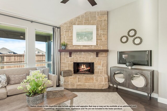 living area featuring vaulted ceiling, a ceiling fan, a stone fireplace, wood finished floors, and baseboards