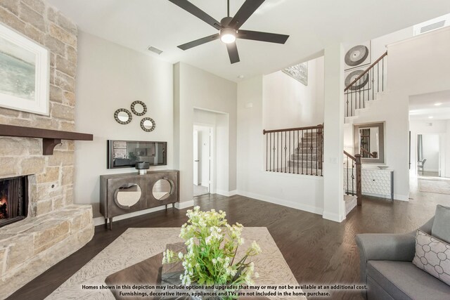 living area featuring stairs, ceiling fan, a high ceiling, wood finished floors, and a fireplace