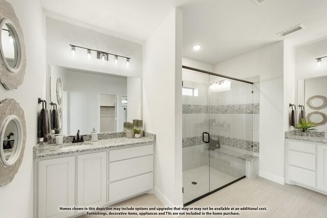 full bath with a stall shower, two vanities, and baseboards