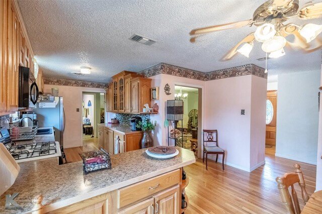 350 County Road 606 Unit B, Tuscola, TX 79562 - kitchen with black microwave, glass insert cabinets, a peninsula, ceiling fan, and a textured ceiling