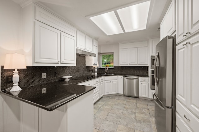 kitchen featuring appliances with stainless steel finishes, a sink, decorative backsplash, white cabinetry, and a peninsula