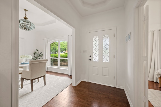 entryway featuring dark wood-type flooring, ornamental molding, a chandelier, and a tray ceiling