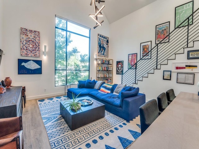 living room featuring stairway, wood finished floors, baseboards, and high vaulted ceiling