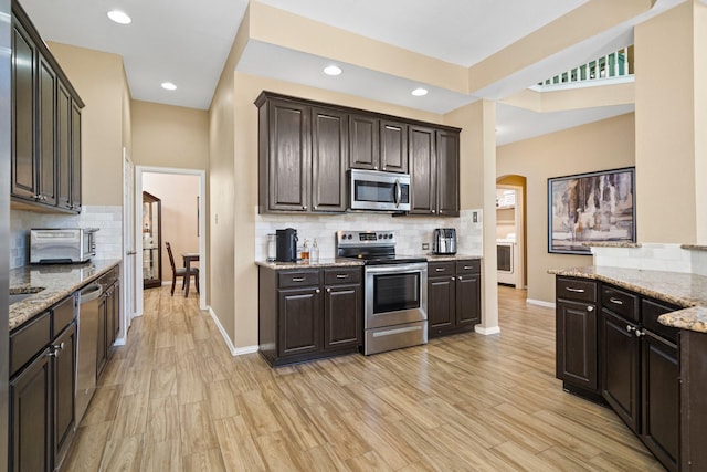 2499 Streamside Ct, Frisco, TX 75036 - kitchen with appliances with stainless steel finishes, arched walkways, tasteful backsplash, baseboards, and dark brown cabinets