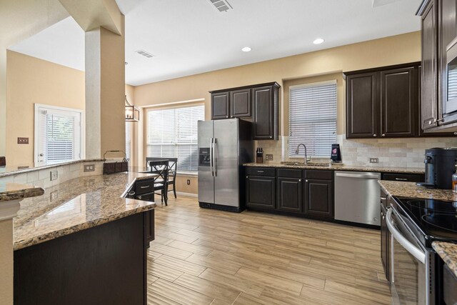 2499 Streamside Ct, Frisco, TX 75036 - kitchen with stainless steel appliances, a sink, backsplash, light stone counters, and plenty of natural light