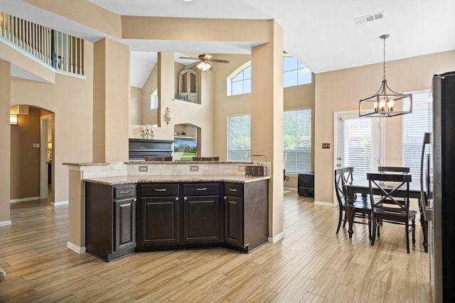 2499 Streamside Ct, Frisco, TX 75036 - kitchen with freestanding refrigerator, arched walkways, ceiling fan, a high ceiling, and light stone counters