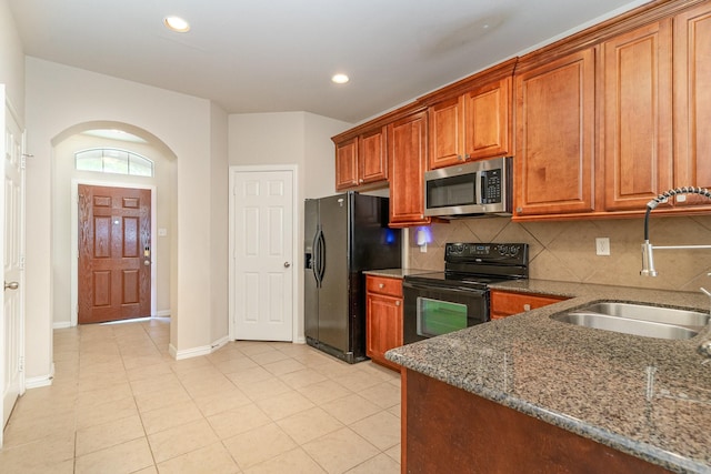 3644 Vienna St, Irving, TX 75038 - kitchen featuring black appliances, a sink, dark stone counters, backsplash, and brown cabinets