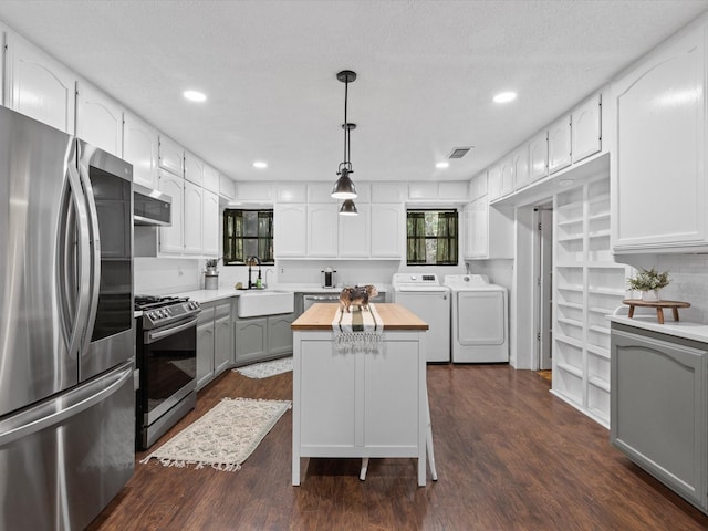 138 Selma Rd, Bowie, TX 76230 - kitchen featuring appliances with stainless steel finishes, washer and dryer, butcher block countertops, a sink, and dark wood-style flooring