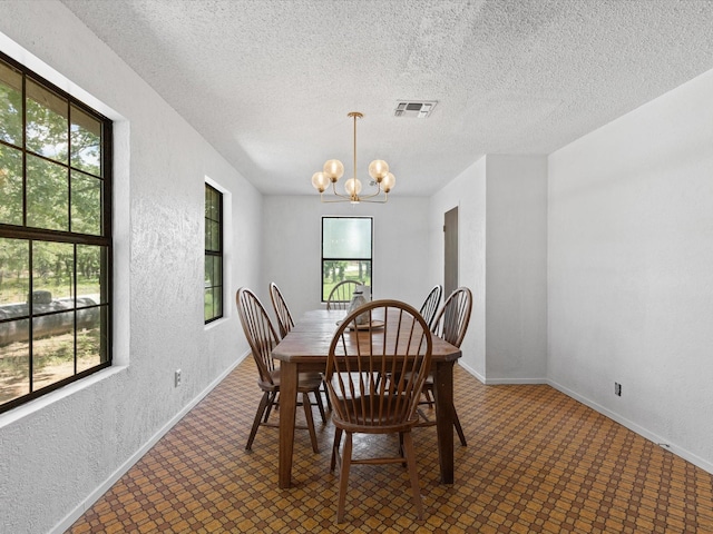 138 Selma Rd, Bowie, TX 76230 - dining area with a chandelier, a textured ceiling, a textured wall, baseboards, and tile patterned floors