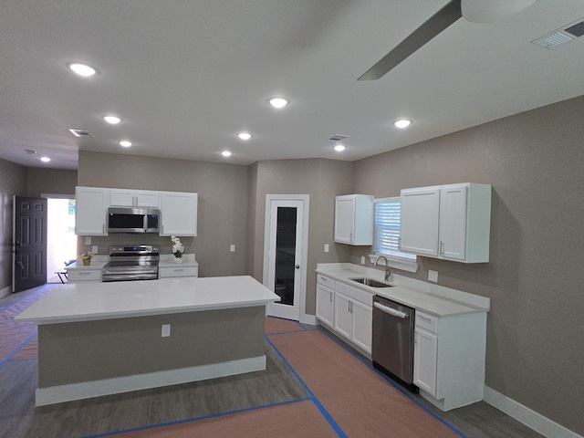 kitchen featuring appliances with stainless steel finishes, a sink, baseboards, white cabinets, and recessed lighting